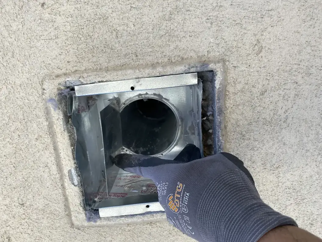 Joe's Window Cleaning technician cleaning inside an exterior dryer vent duct