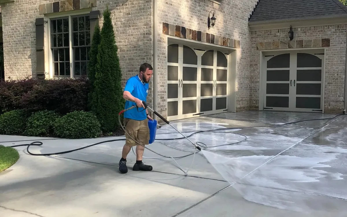 Joe's Window Cleaning technician pressure washing a residential driveway
