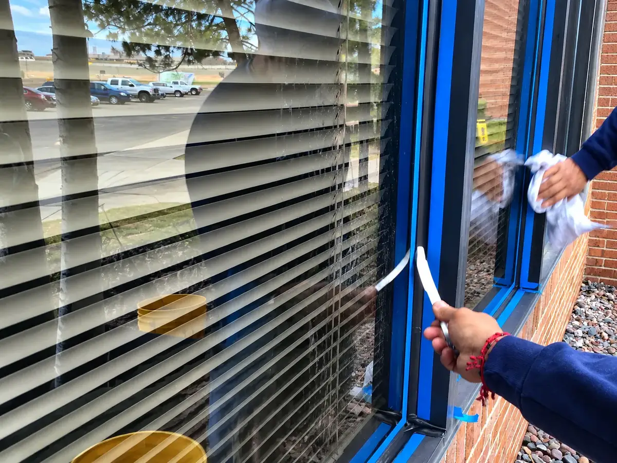 Joe's Window Cleaning technicians finishing caulk work around a commercial window
