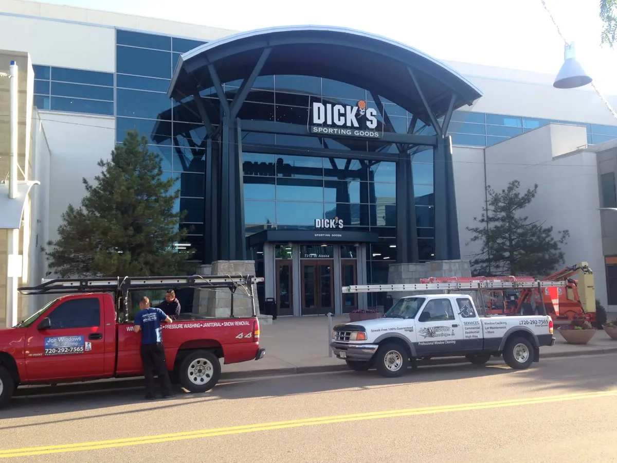 Joe's Window Cleaning crew and trucks at the entrance of a large commercial storefront