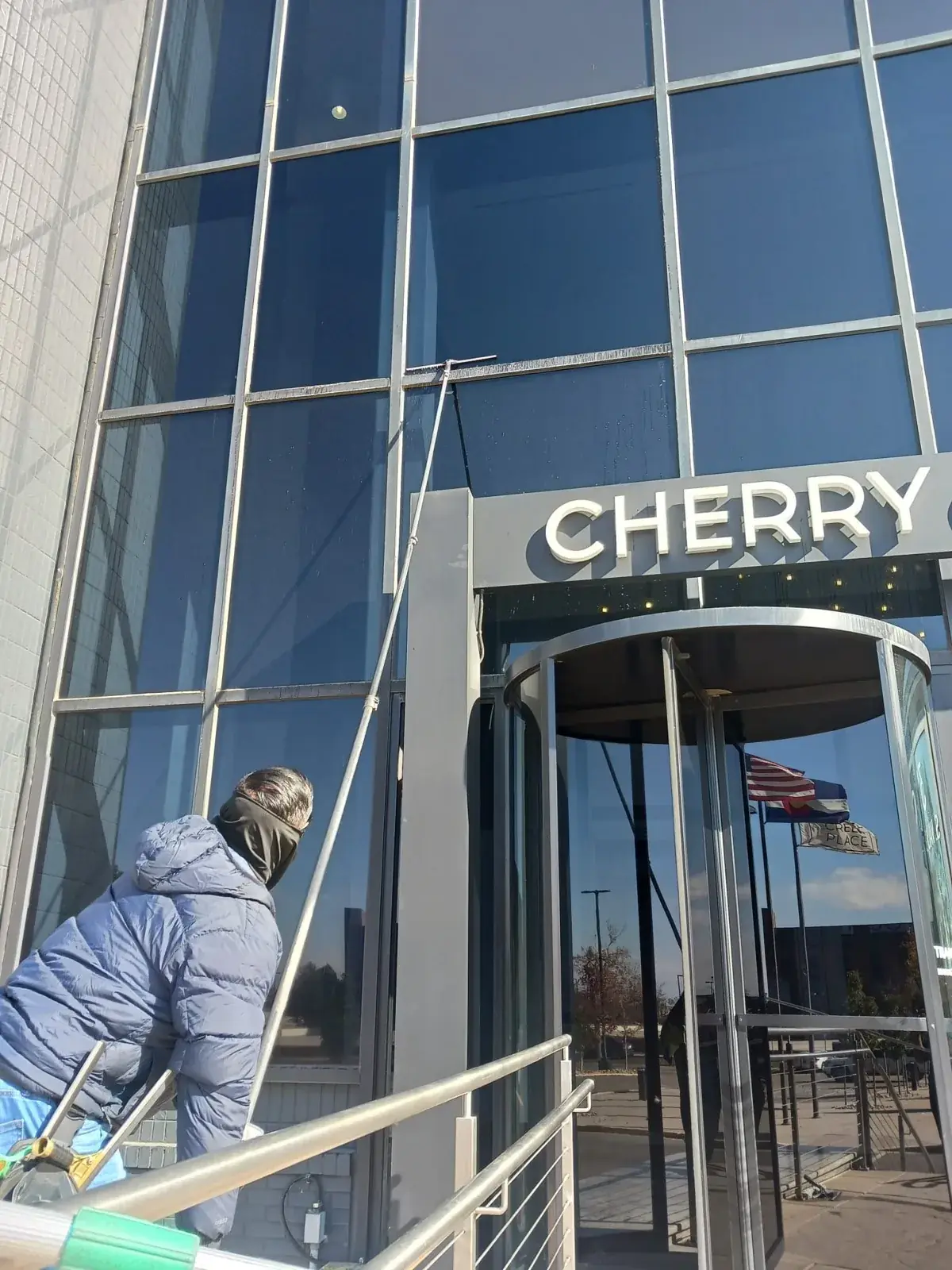 Joe's technician cleaning the tall glass curtain wall above a revolving door