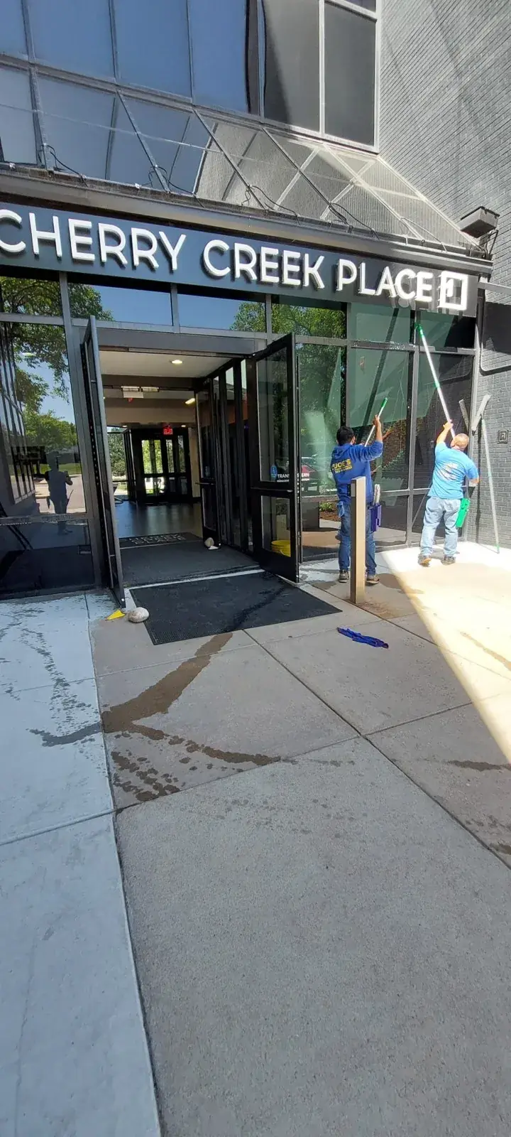 Two Joe's technicians cleaning the glass at a commercial building entrance