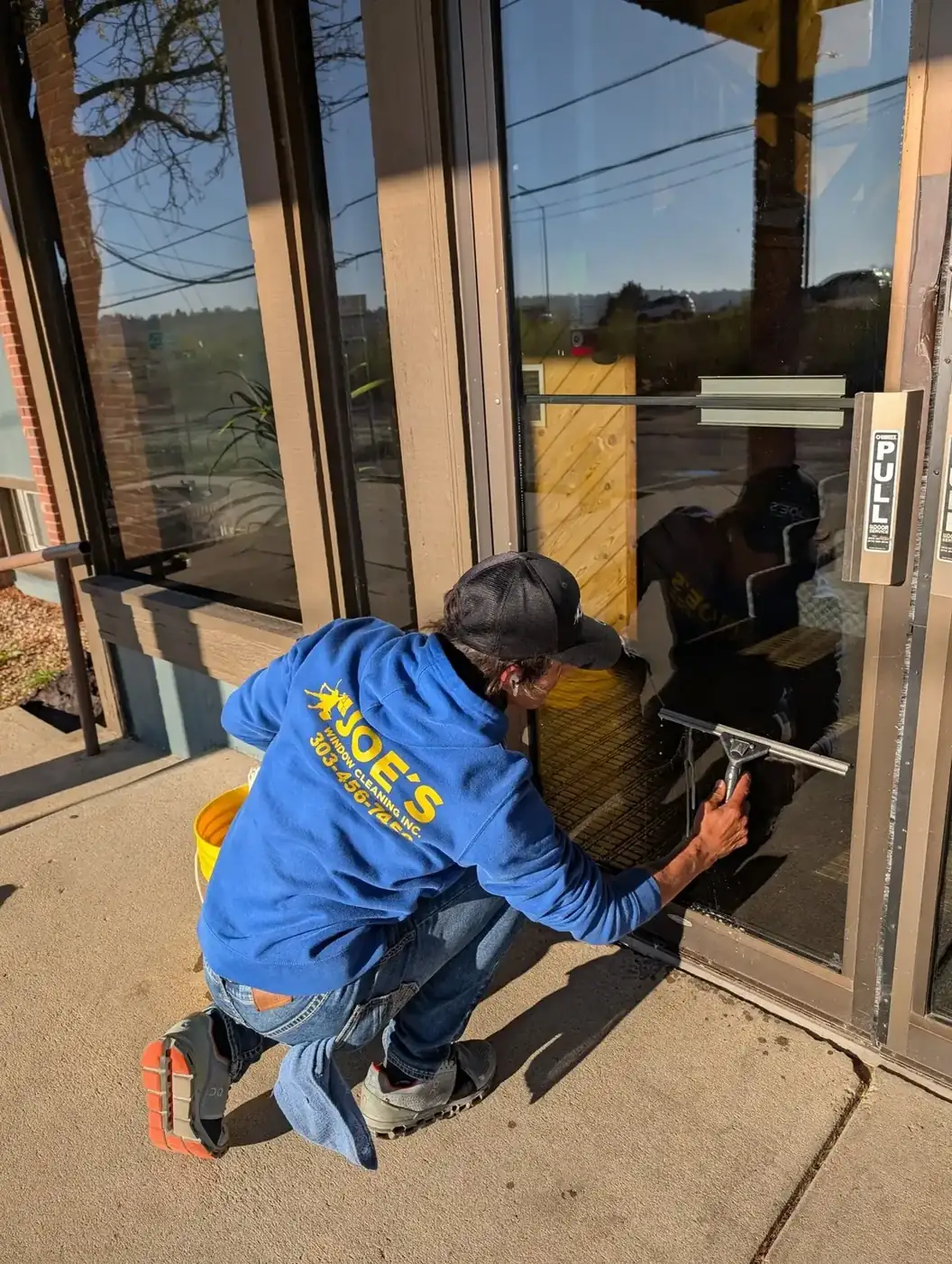 Joe's technician squeegeeing the glass door of a commercial storefront