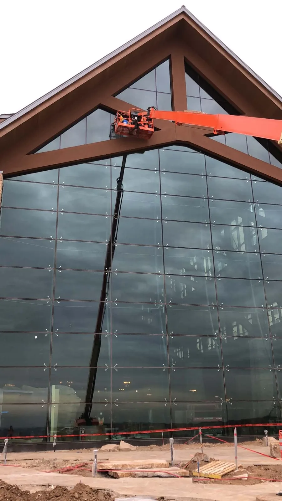 Boom lift cleaning the tall glass gable of a new building
