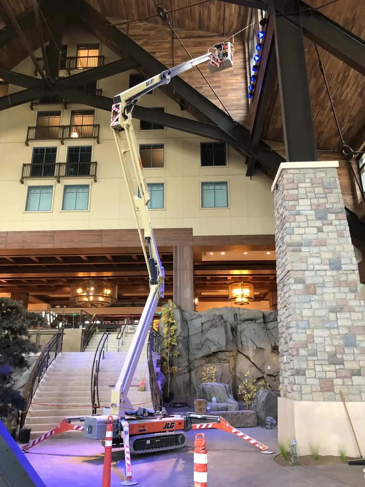 Compact boom lift cleaning high windows inside a grand lodge lobby