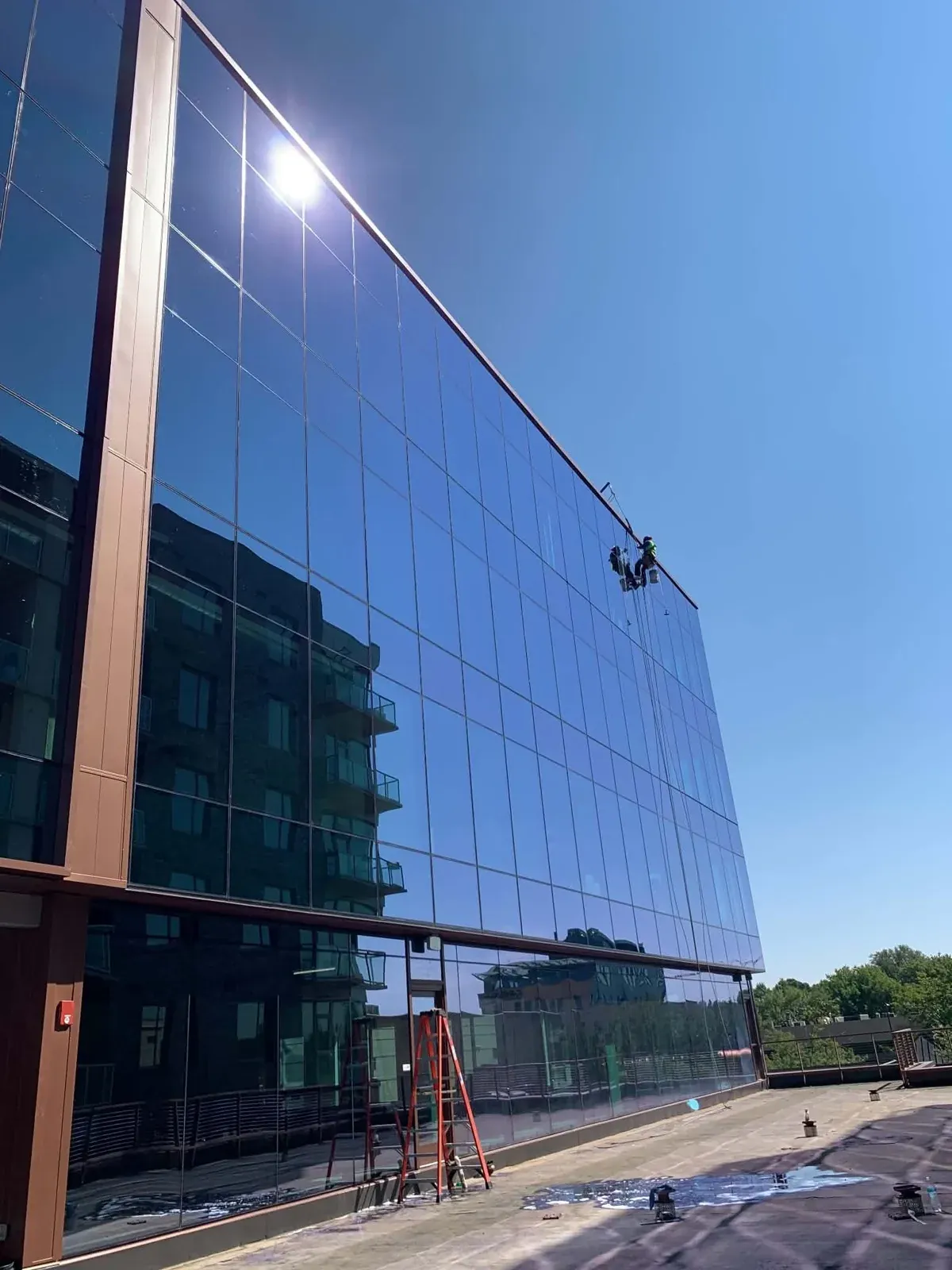 Rope access technicians cleaning a large mirrored glass facade