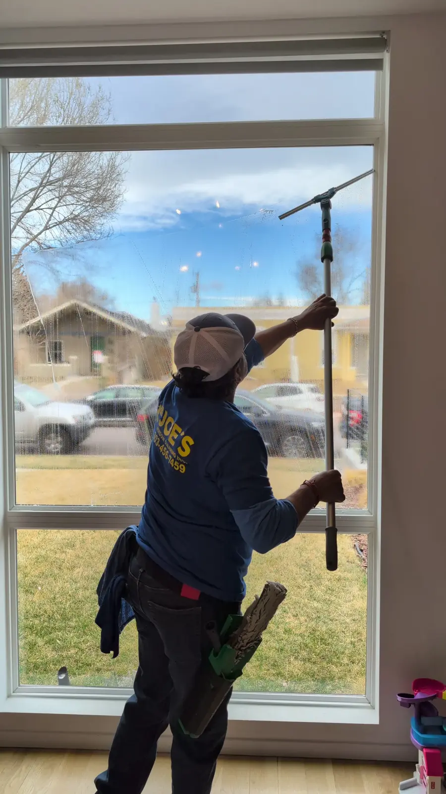 Joe's Window Cleaning technician squeegeeing an interior residential window
