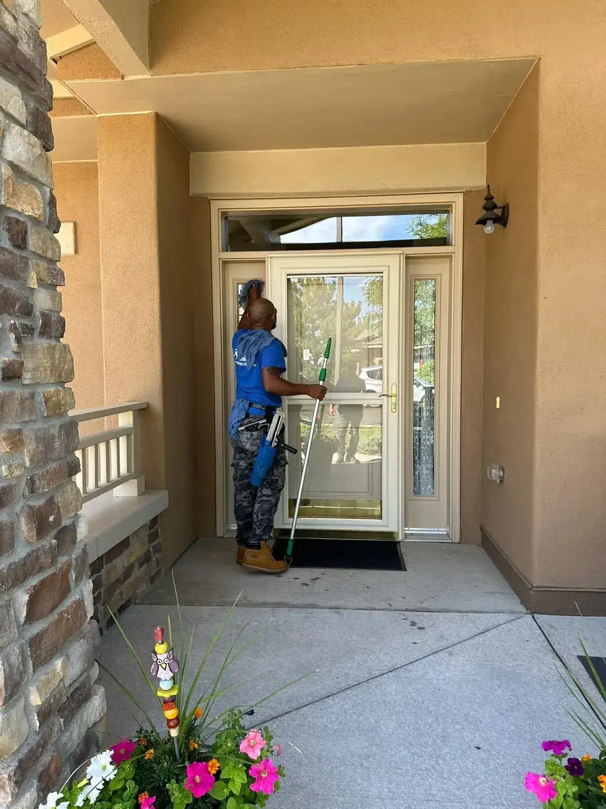Joe's technician cleaning the glass storm door at a home's front entry