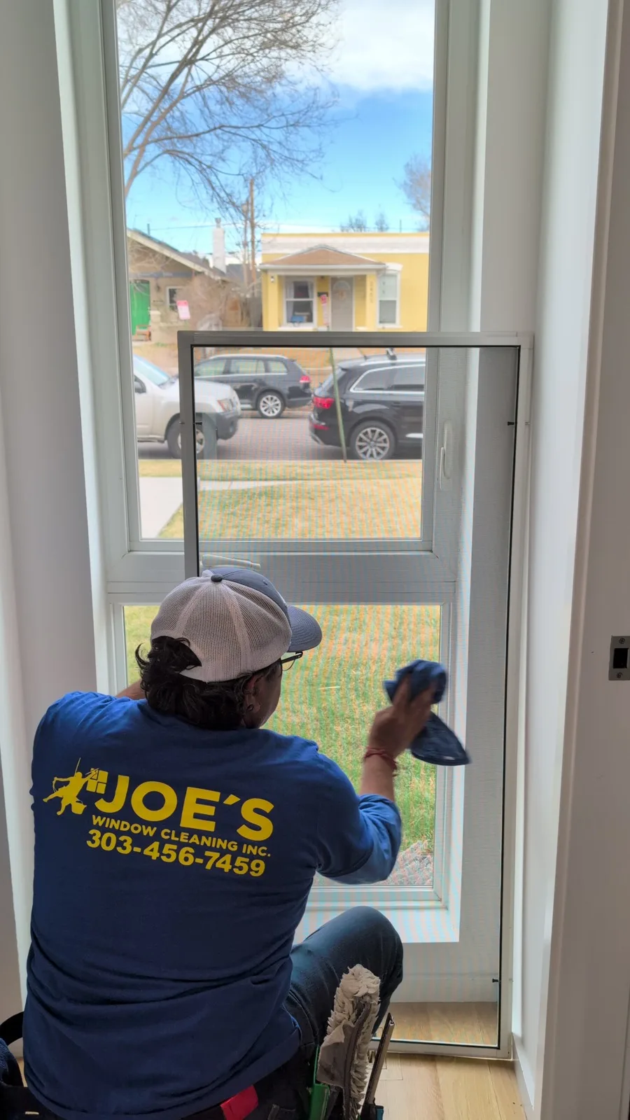 Joe's technician wiping down a tall interior window in a home